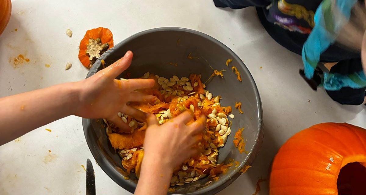 Cubs scooping seeds out of pumpkins at a carving night in the Annamoe Centre