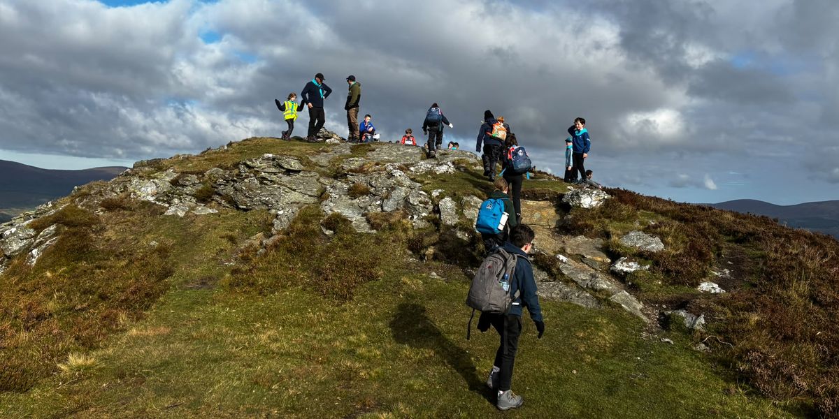 Cubs and leaders reaching the rocky summit of Scarr on a sunny autumn day